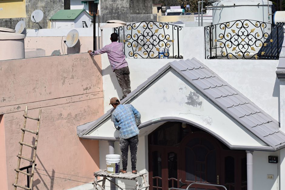 Two workers painting on a building.