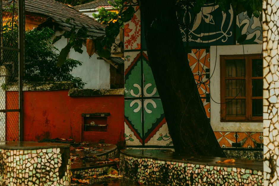 Painted wall with colorful patterns and a tree in front.