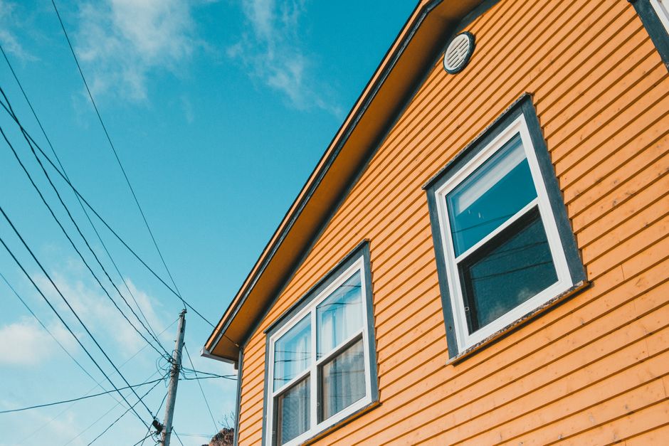 Yellow wooden house exterior seen from below against the sky.