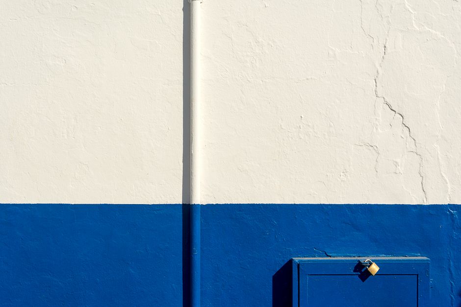 Painted white and blue wall with a padlock on it.