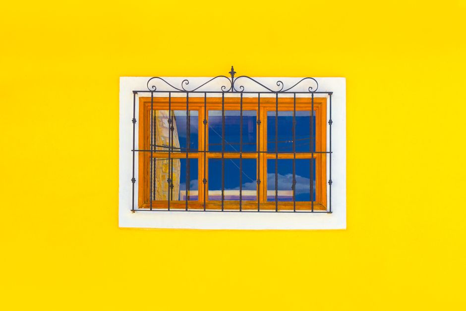Small wood-framed window on a yellow painted wall.