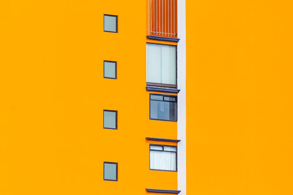 Orange painted house front with small windows.
