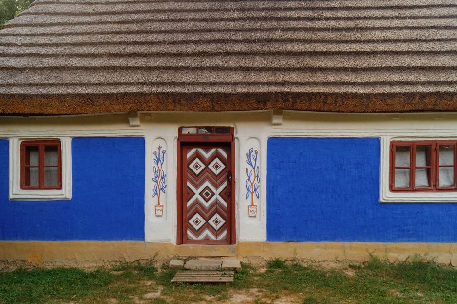 Small house with painted blue walls and a thatched roof.